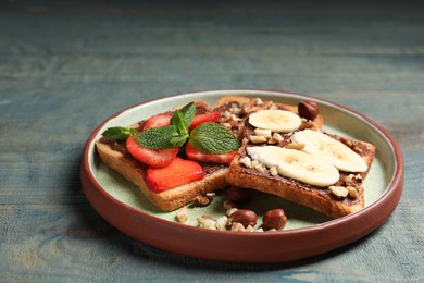 Photo of Tasty toasts with chocolate spread, nuts, strawberries, banana and mint served on wooden table
