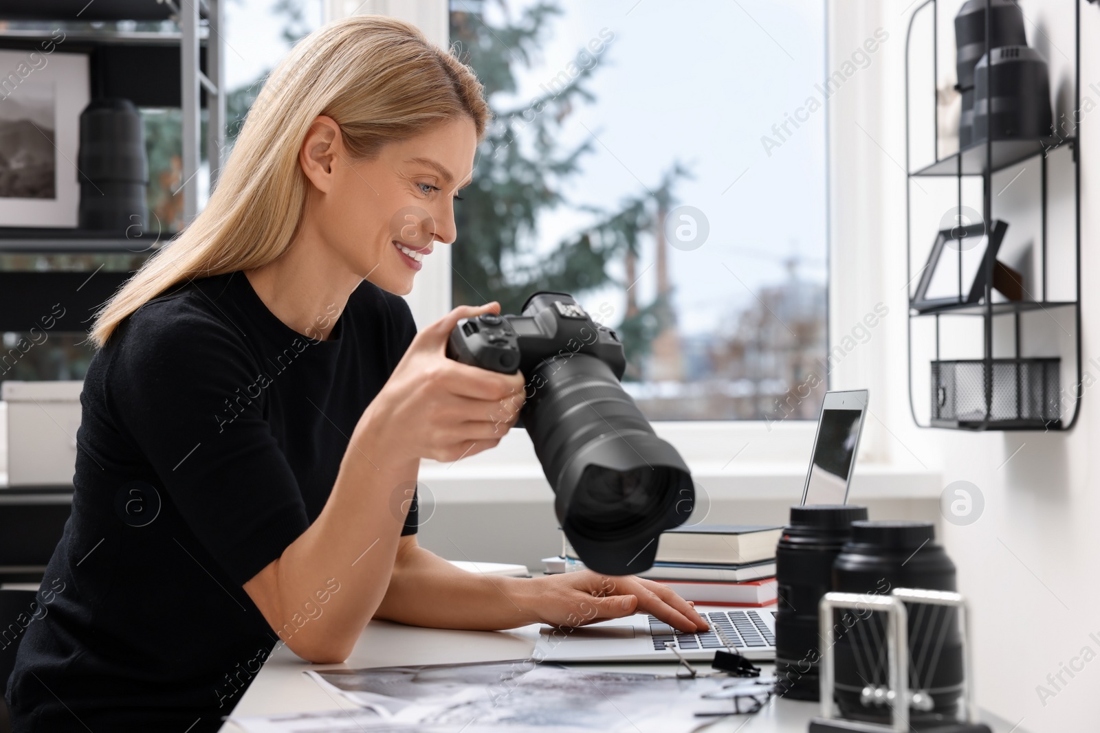 Photo of Professional photographer with digital camera at table in office