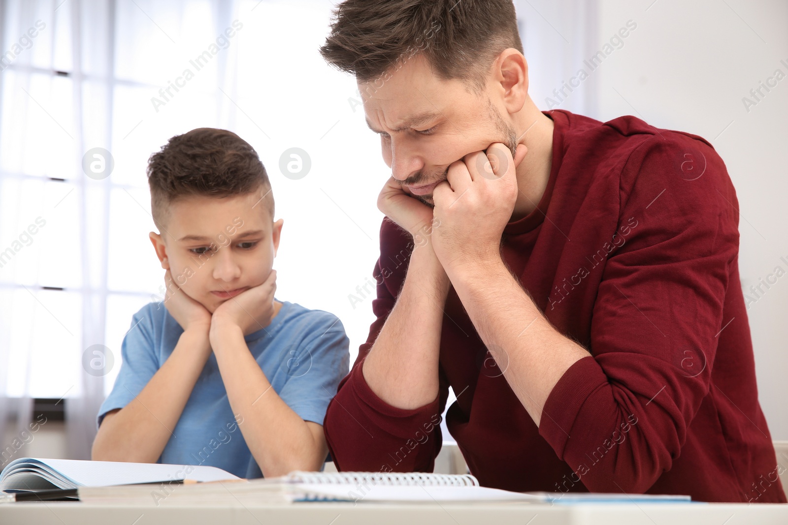 Photo of Dad helping his son with difficult homework assignment in room