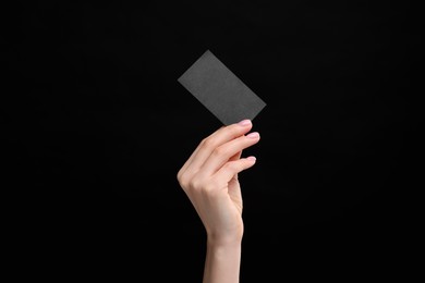 Woman holding blank business card on black background, closeup. Space for text