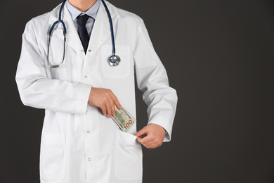 Photo of Doctor putting bribe into pocket on black background, closeup. Corruption in medicine