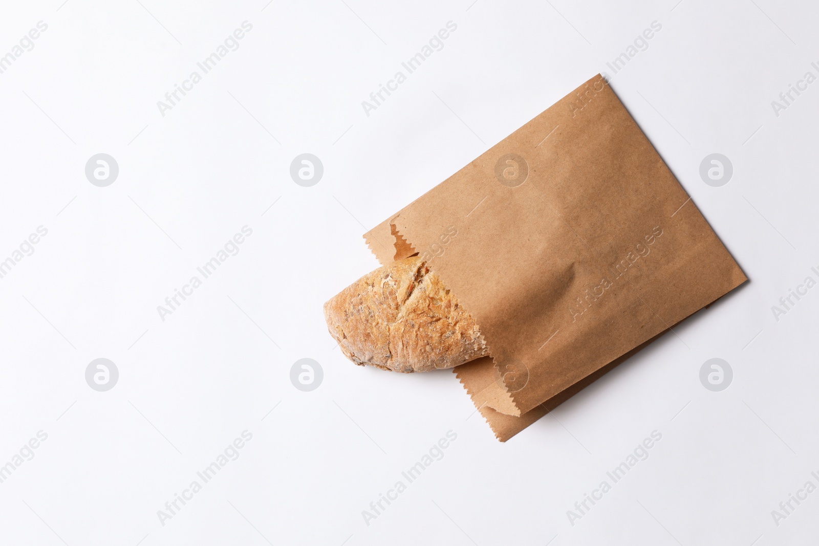 Photo of Paper bag with bread on white background, top view. Space for text