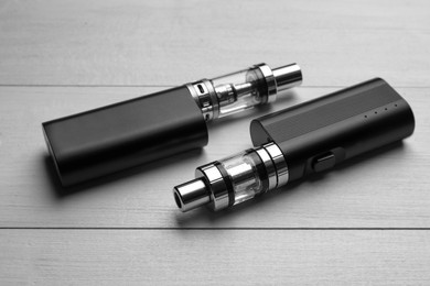 Photo of Two electronic cigarettes on white wooden table