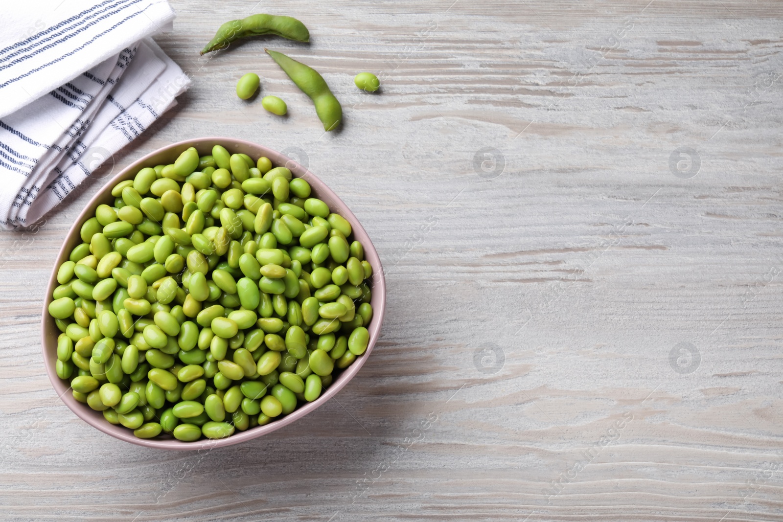 Photo of Organic edamame beans on light wooden table, flat lay. Space for text