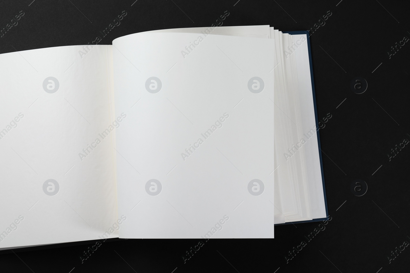 Photo of One open photo album on black background, top view. Space for text