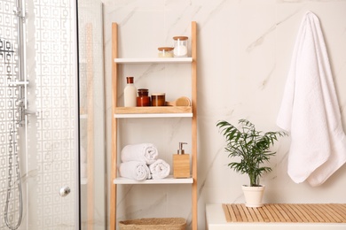 Photo of Soft towels and different toiletries on decorative ladder in bathroom. Interior design