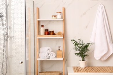 Soft towels and different toiletries on decorative ladder in bathroom. Interior design