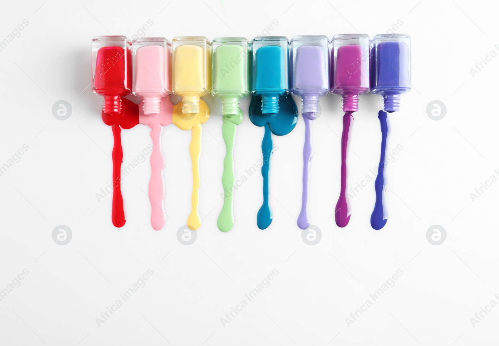 Photo of Spilled colorful nail polishes and bottles on white background, top view