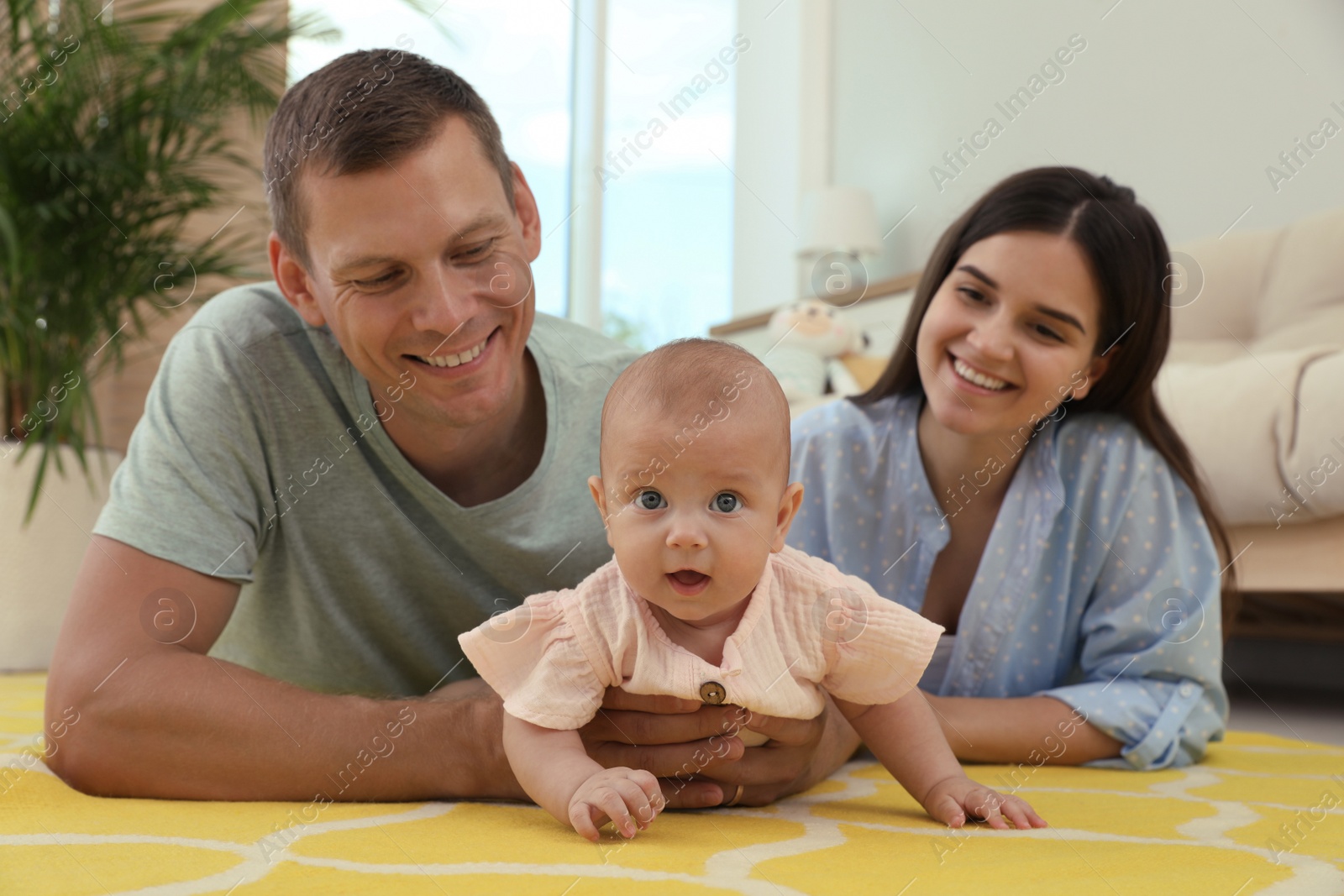 Photo of Happy family with their cute baby in living room at home