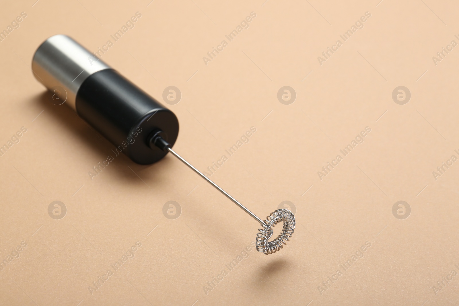 Photo of Milk frother wand on light brown background, space for text