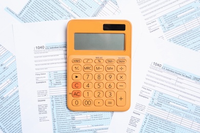 Photo of Orange calculator on documents, top view. Tax accounting