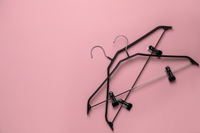 Empty hangers with clips on pink background, flat lay. Space for text