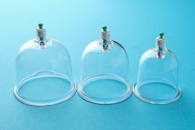 Photo of Plastic cups on light blue background. Cupping therapy