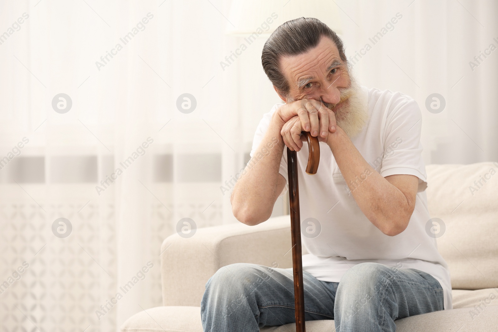 Photo of Senior man with walking cane on sofa at home