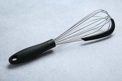 Metal whisk on gray table. Kitchen tool