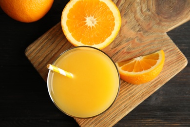 Photo of Glass with orange juice and fresh fruit on wooden board, top view