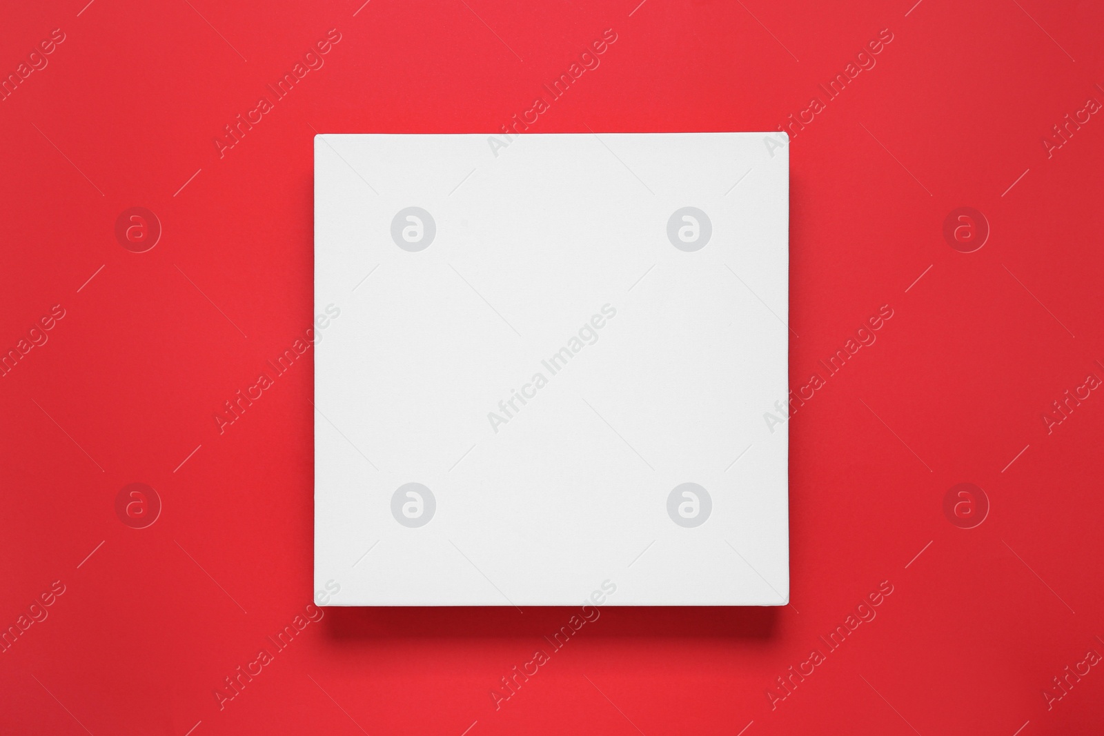 Photo of Blank canvas on red background, top view. Space for design