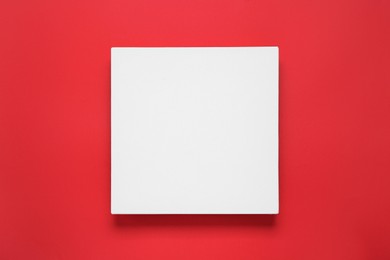 Photo of Blank canvas on red background, top view. Space for design