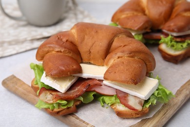 Tasty crescent roll with brie cheese, ham and bacon on white table, closeup