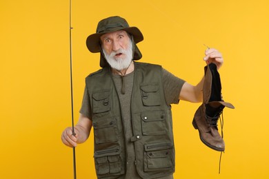 Photo of Confused fisherman with rod and old boot on yellow background