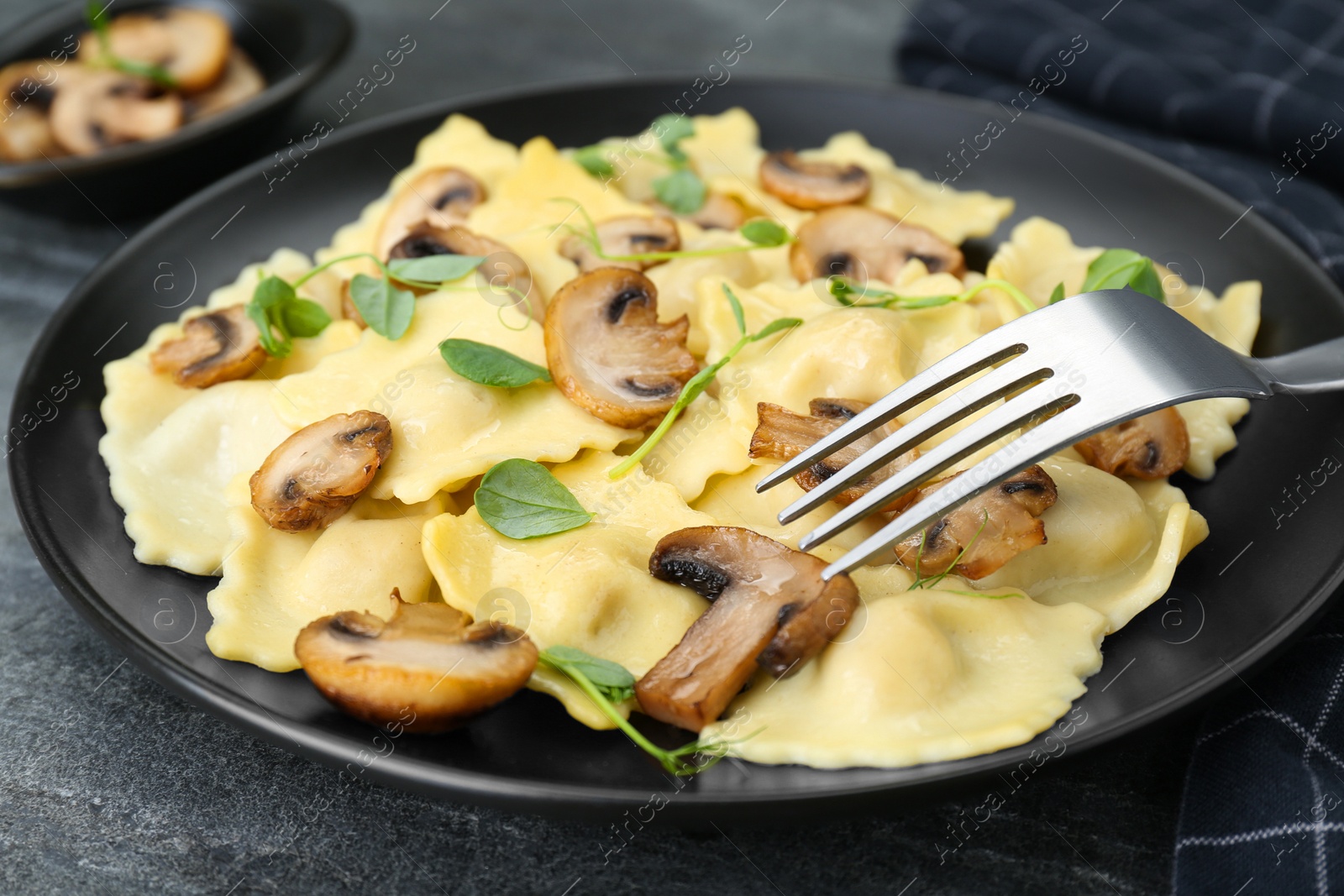 Photo of Delicious ravioli with mushrooms served on grey table, closeup