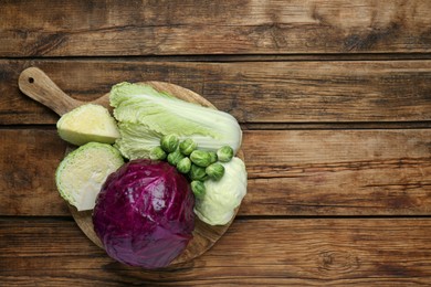 Photo of Different types of cabbage on wooden table, top view. Space for text