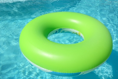 Bright inflatable ring floating in swimming pool on sunny day