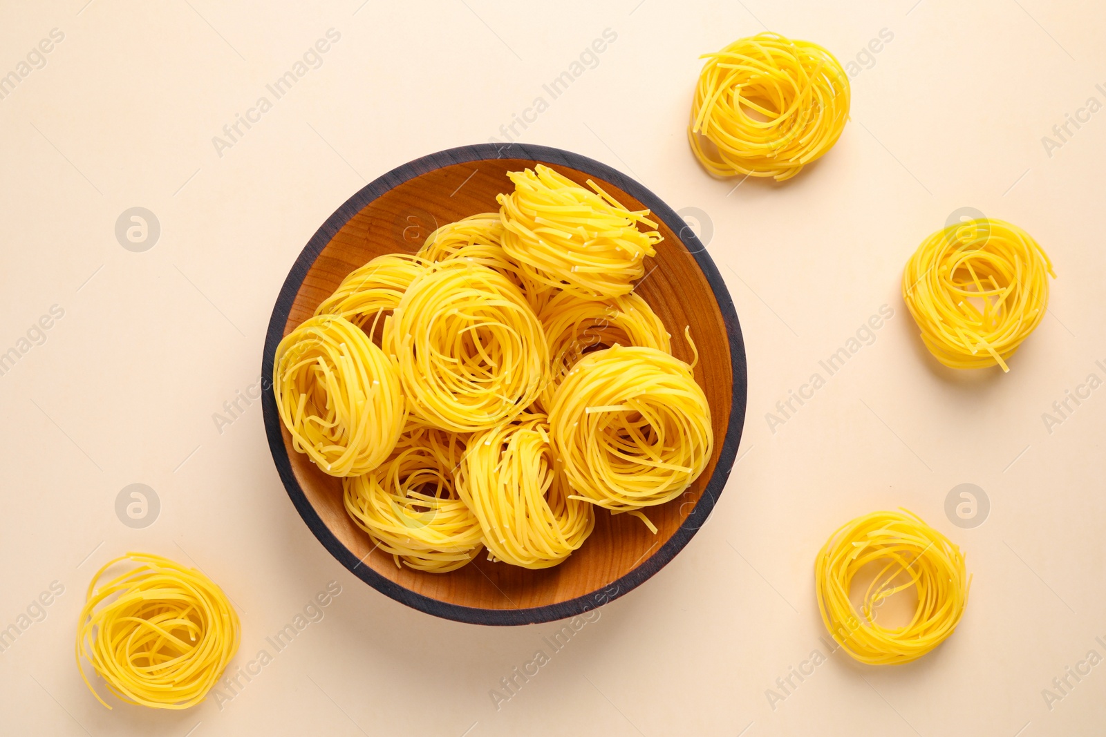 Photo of Angel hair pasta on beige background, flat lay