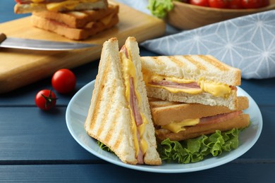 Photo of Tasty sandwiches with ham, melted cheese and lettuce on blue wooden table