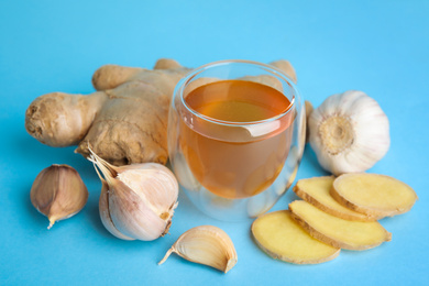 Photo of Fresh garlic and other natural cold remedies on light blue background