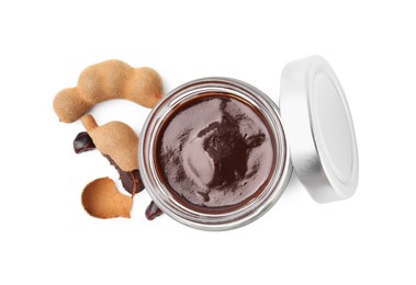 Photo of Jar of tasty tamarind sauce and fresh pods isolated on white, top view