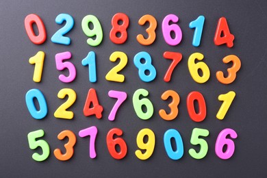 Colorful numbers on dark gray background, flat lay