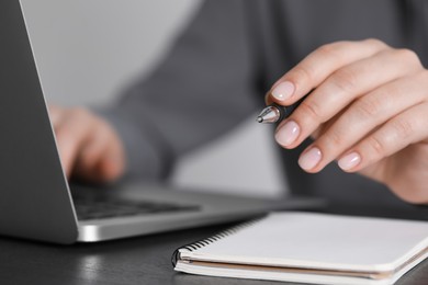 Woman with pen working on laptop, closeup. Electronic document management