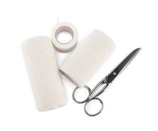 Photo of Medical bandage rolls, sticking plaster and scissors on white background, top view