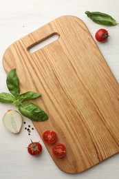 Photo of Cutting board, basil, onion, pepper and tomatoes on white wooden table, flat lay. Space for text