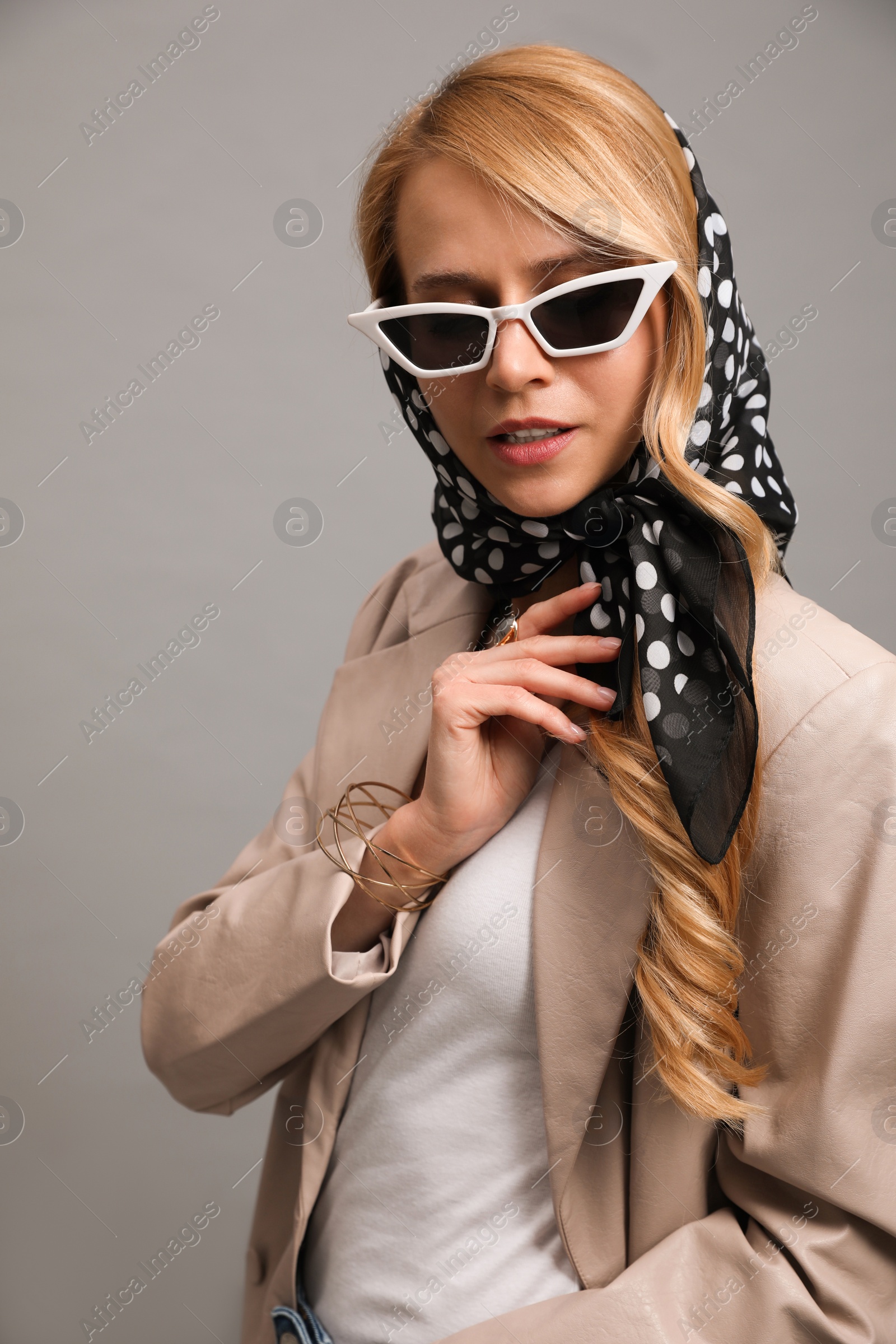 Photo of Young woman with sunglasses and stylish bandana on grey background