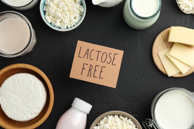 Photo of Dairy products and card with phrase Lactose free on black textured table, flat lay