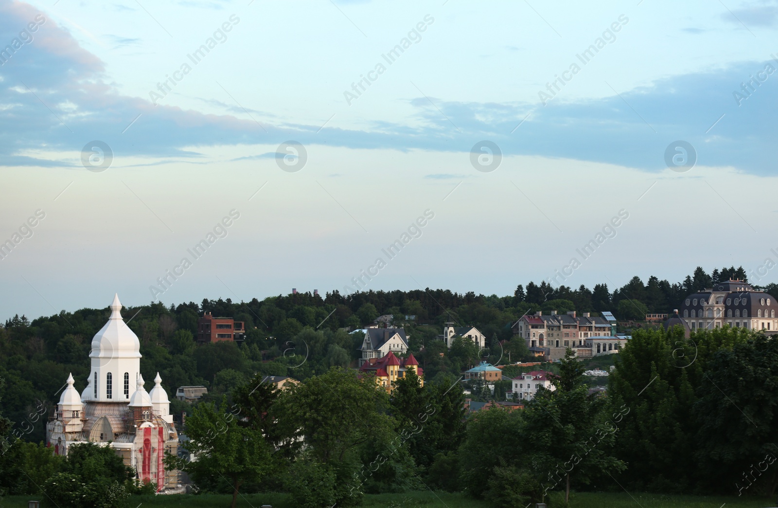 Photo of KYIV, UKRAINE - MAY 23, 2019: Christian church with domes at buildings among trees