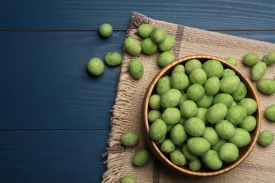 Photo of Tasty wasabi coated peanuts on blue wooden table, flat lay. Space for text