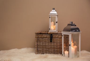 Decorative lanterns and wicker chest on fuzzy rug near brown wall, space for text. Interior elements