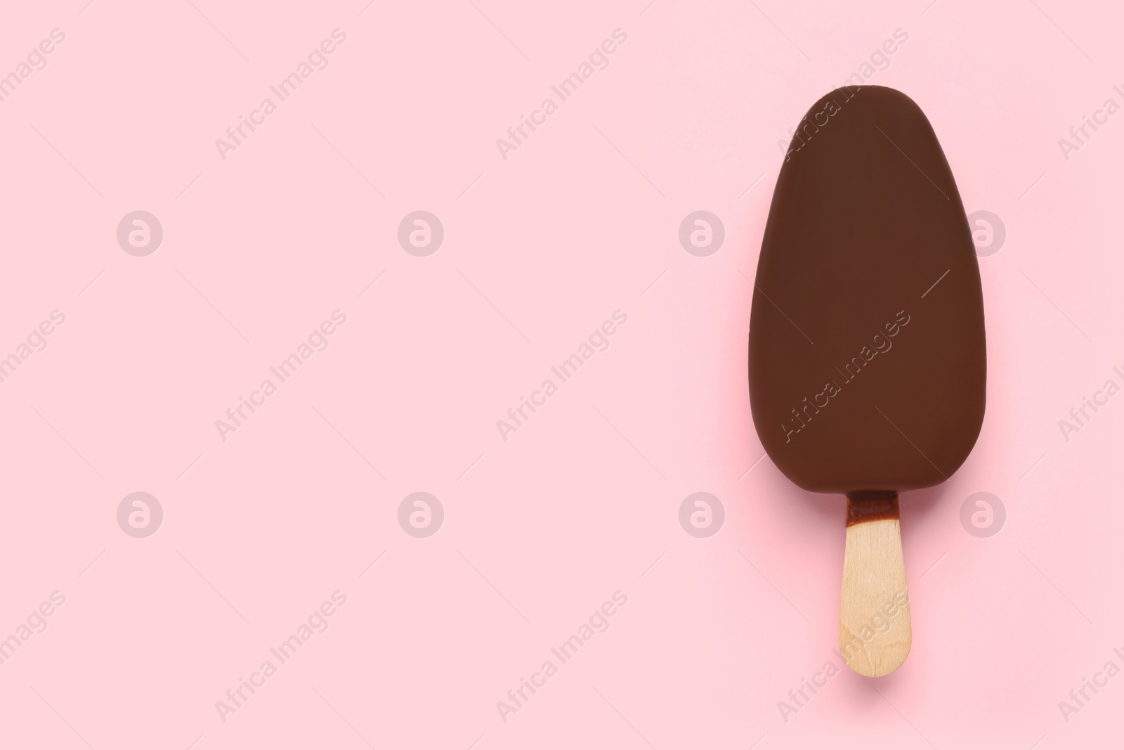 Photo of Ice cream glazed in chocolate on pink background, top view. Space for text