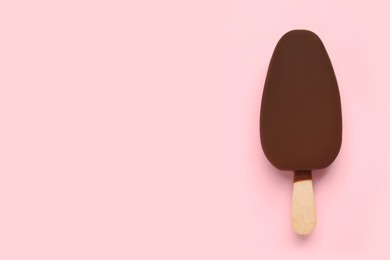 Photo of Ice cream glazed in chocolate on pink background, top view. Space for text