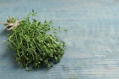 Photo of Bunch of aromatic thyme on light blue wooden table, closeup. Space for text