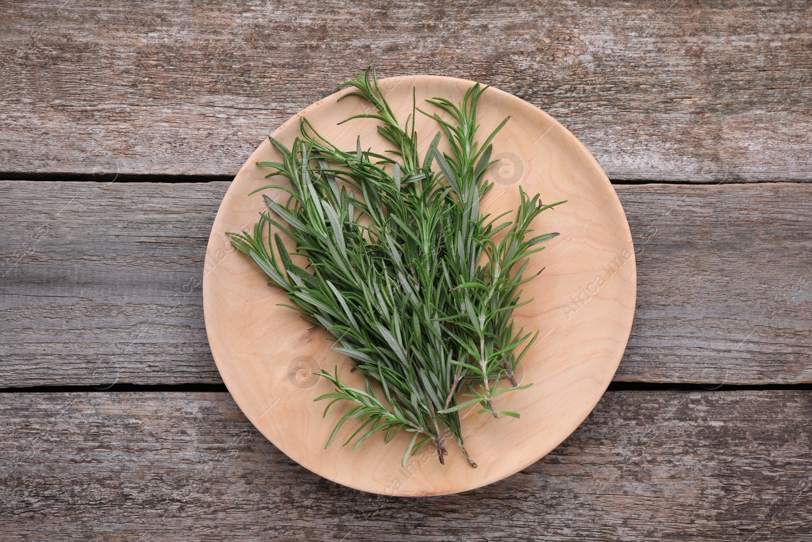 Photo of Sprigs of fresh rosemary on wooden table, top view