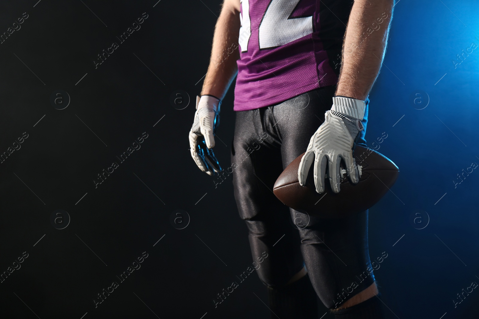 Photo of American football player with ball on dark background, closeup. Space for text