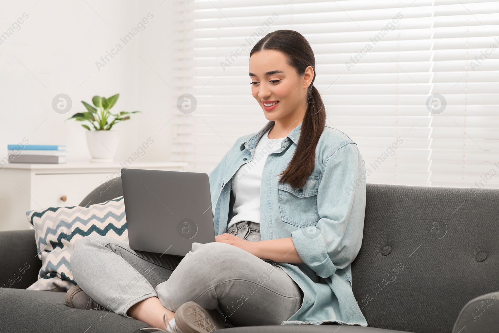 Photo of Woman using laptop on couch at home