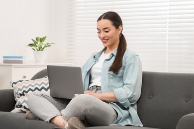 Woman using laptop on couch at home