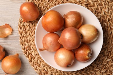 Photo of Many ripe onions on wooden table, flat lay