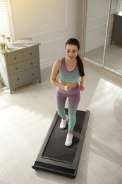 Sporty woman training on walking treadmill at home, above view