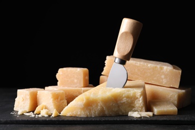 Photo of Parmesan cheese with slate plate and knife on table, closeup